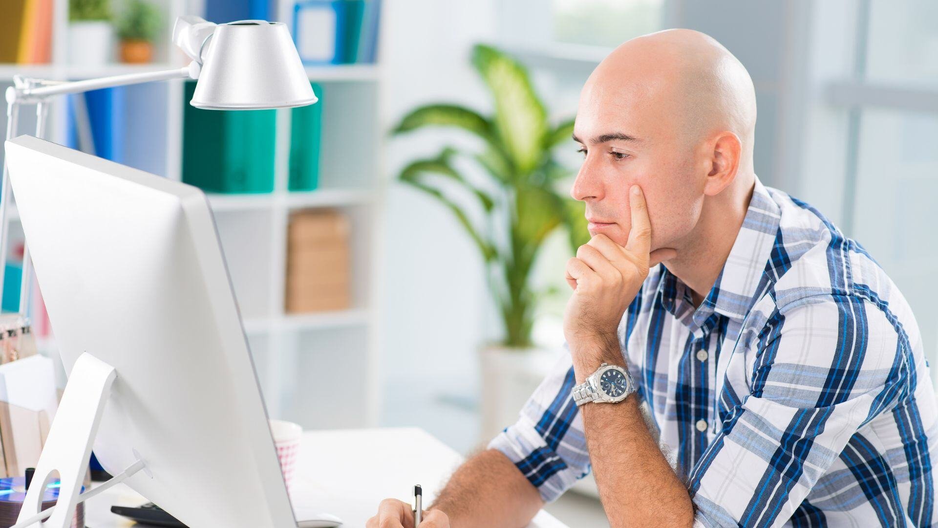 man looking at his computer screen in a contemplative way