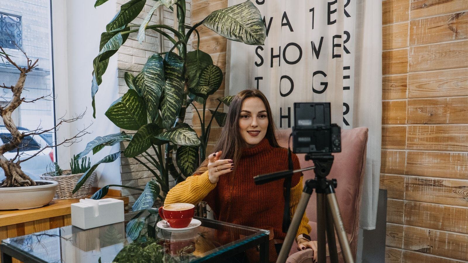 Woman sitting in front of a tripod camera recording a video